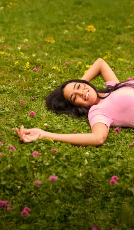 Woman relaxing in a field of flowers, carefree and free from allergy symptoms.